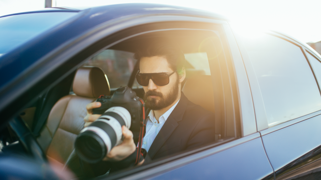 Private investigator sitting in his car holding a camera.